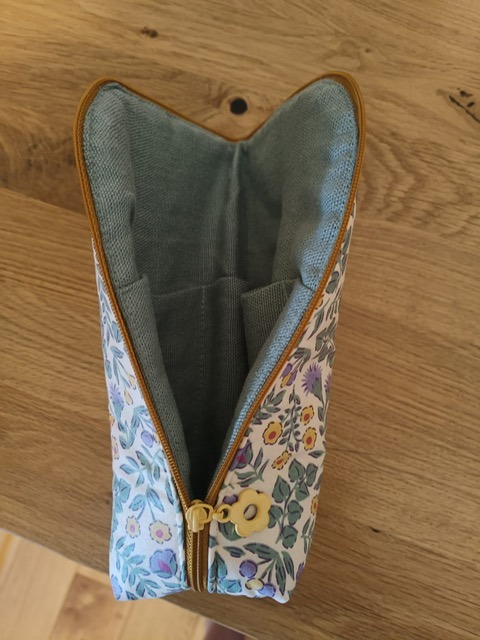 Trousse ouverte en tissu fleuri, doublée de bleu, avec une fermeture éclair dorée