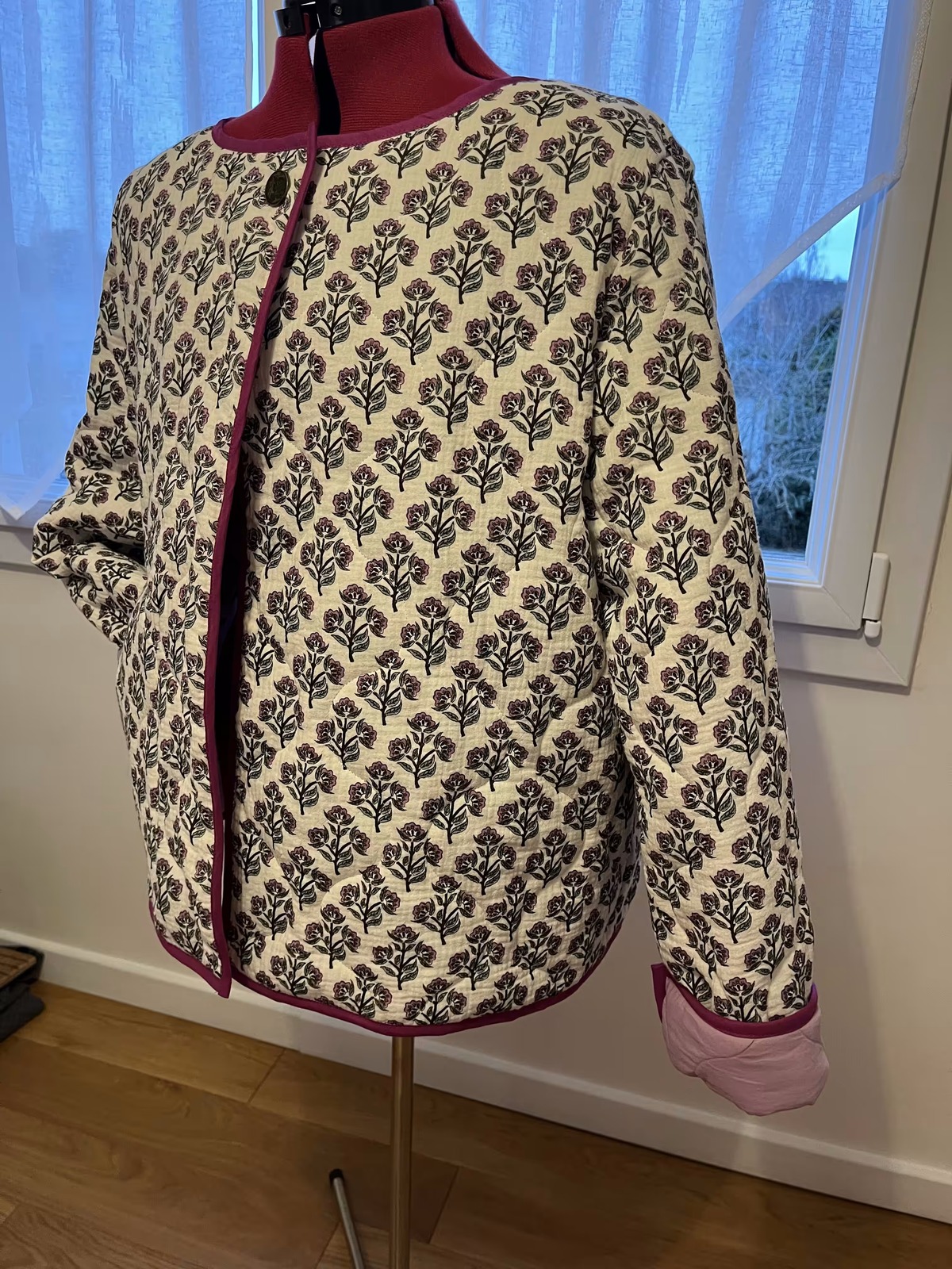 Veste matelassée à motifs, bordée de bordeaux, sur un mannequin de couture