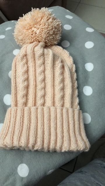 Bonnet crème tricoté en torsades, avec un gros pompon