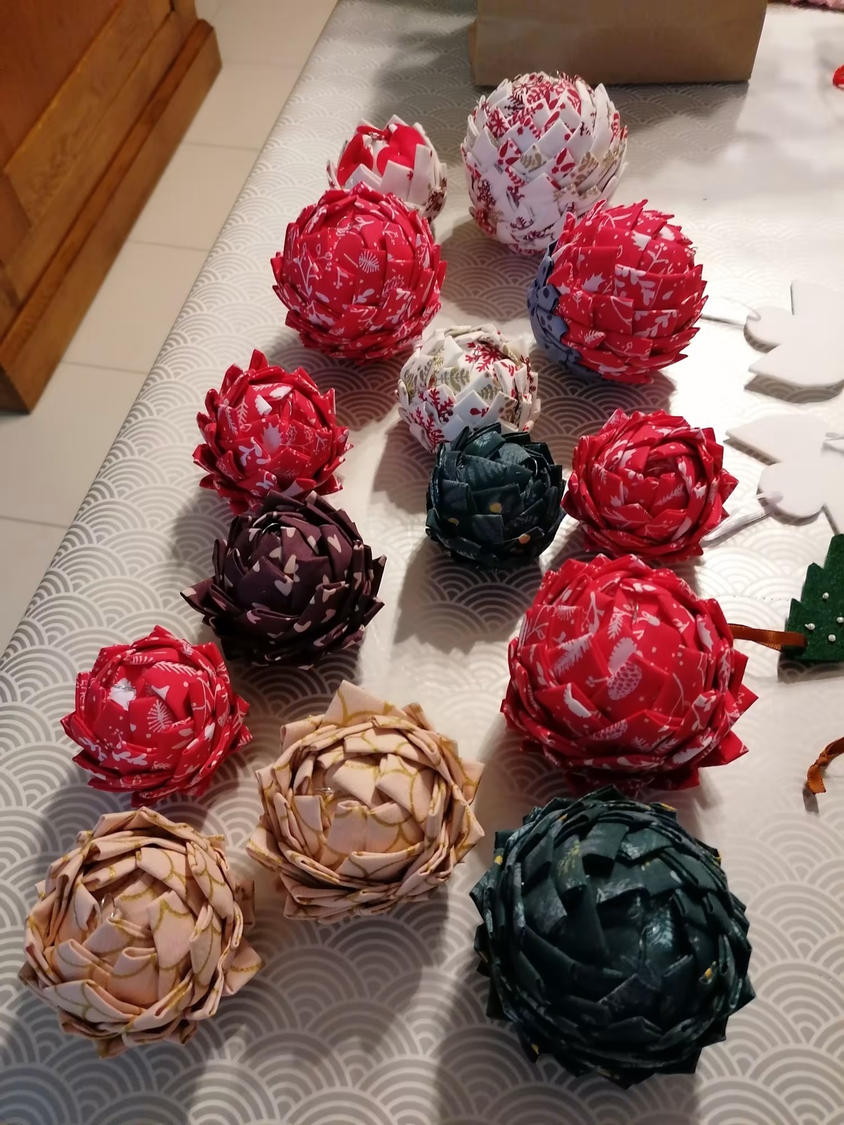 Une douzaine de boules en tissu plié, rouges, vertes et beiges