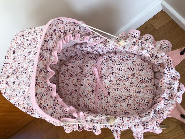 Couffin garni de tissu rose à petites fleurs, bordé d'un volant