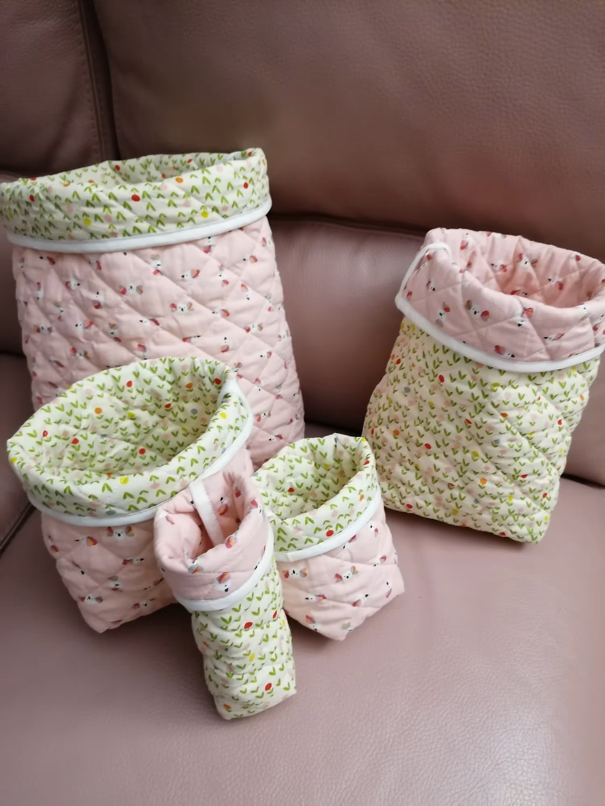 Quatre paniers de tailles différentes en tissu matelassé vert et rose
